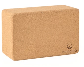 May include: A natural cork yoga block with a brown, textured surface. The block has the word "hamaste" printed on the side in a brown font.