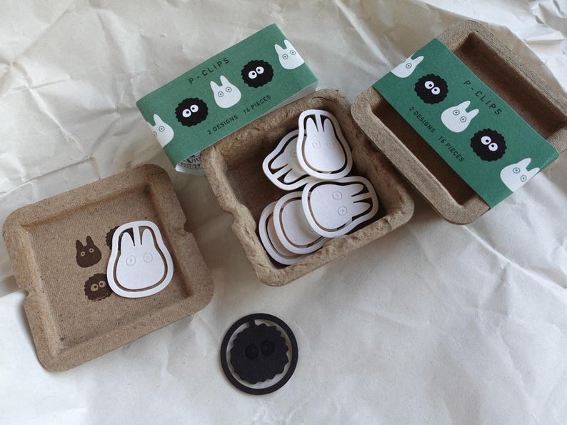 May include: A set of 14 paper clips featuring two designs: a white Totoro and a black Totoro. The clips are packaged in a brown cardboard box with a green and white label that reads "P-Clips 2 Designs 14 Pieces".