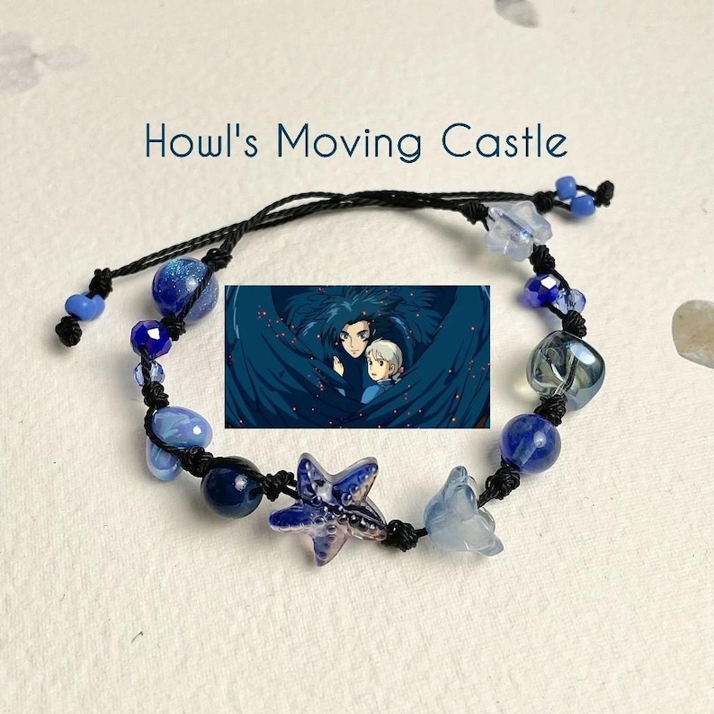 Puede incluir: Un brazalete de cuerda negra con cuentas de vidrio azul y transparente, un dije de estrella azul y blanco, y un dije con una escena de la pel&iacute;cula animada "El castillo ambulante".