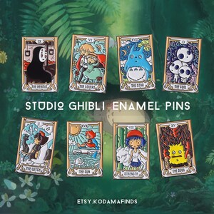 May include: Set of ten enamel pins featuring characters from Studio Ghibli films. Each pin is shaped like a tarot card and features a different character and title. The pins are colorful and detailed.