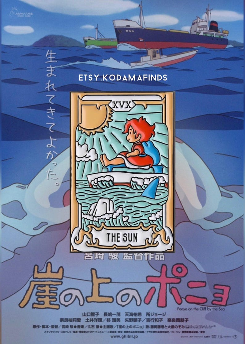 May include: A gold and blue enamel pin featuring a character from the animated film "Ponyo" sitting on a boat with a shark fin in the water. The pin is a depiction of the "The Sun" card from the tarot deck. The text "生まれてきてよかった" is written in Japanese on the left side of the pin. The text "The Sun" and "呂崎駿監督作品" are written in English and Japanese on the bottom of the pin.