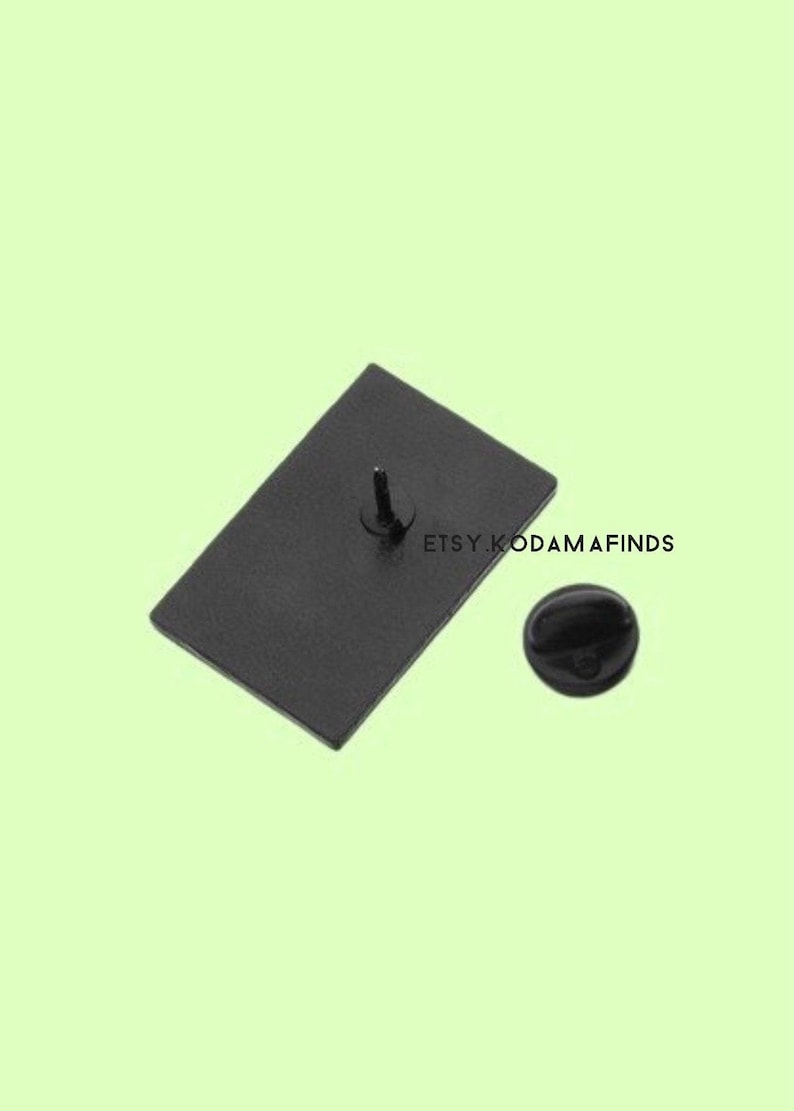 May include: Black enamel pin with a rectangular shape and a silver pin back. The pin is on a light green background.