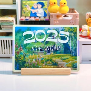 May include: A 2023 calendar featuring a whimsical illustration of a cottage with a thatched roof, surrounded by lush greenery and flowers. The text "COSY GHIBLI" and "World of Dreams" is printed at the bottom of the calendar.