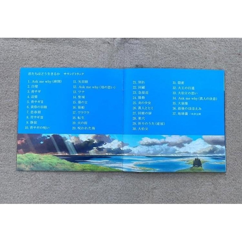 May include: A blue and white booklet with the Japanese text "君たちはどう生きるか サウンドトラック" (Kimitachi wa Dō Ikiru ka Soundtrack) and a list of song titles in Japanese. The booklet features a scenic image of a small island with trees in a body of water.