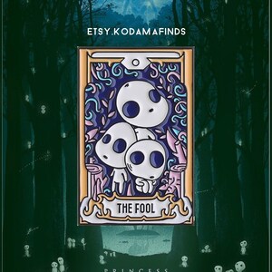 May include: A colorful enamel pin featuring three white Kodama from the movie Princess Mononoke. The pin is shaped like a tarot card with the words "The Fool" on the bottom. The background is a dark green forest.