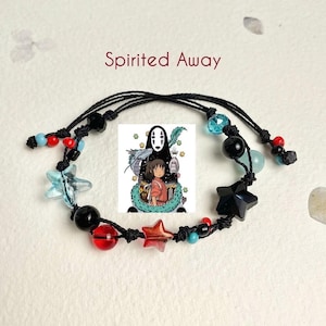 Puede incluir: Un brazalete de cuerda negra con cuentas rojas, azules y negras, y abalorios en forma de estrella. El brazalete presenta un abalorio con una imagen de personajes de la pel&iacute;cula animada "El viaje de Chihiro".