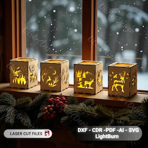 Puede incluir: Cuatro portavelas de madera con escenas invernales cortadas con láser de ciervos y árboles. Cada soporte en forma de cubo tiene una luz cálida y brillante en su interior. Los portavelas se exhiben en un alféizar con un fondo nevado.