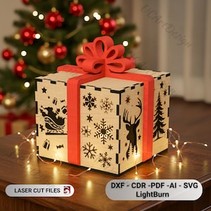May include: A wooden Christmas gift box with laser-cut designs of snowflakes, a reindeer, and a Christmas tree. The box is wrapped with a red ribbon and bow. The text "LASER CUT FILES" and "DXF - CDR -PDF -AI - SVG LightBurn" are visible.