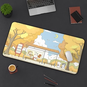 May include: A rectangular mousepad featuring an autumn scene with cartoon animals at a bus stop. The design includes a yellow and orange color palette, trees, a blue sky with clouds and a crescent moon. A white mouse is on the right.