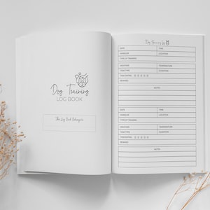 Può includere: Un libro di registro per l'addestramento dei cani in bianco e nero con una semplice illustrazione di un cane sulla copertina. Il libro ha sezioni per la data, l'addestratore, il tipo di addestramento, il tempo, il tipo di compito, la valutazione del compito, la ricompensa e le note.