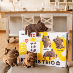 May include: A 3D cardboard puzzle set titled Kittens Trio featuring three assembled brown cat figures. The box displays the text 3D Puzzle, Kittens Trio, 3in1, 254 pieces, 140 level, and images of a walking kitten, maneki kitten, and sleepy kitten.