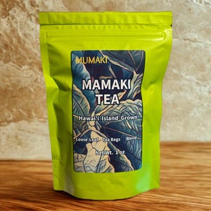 May include: A bright green pouch of Mamaki Tea. The label features the text "MUMAKI MAMAKI TEA" and "Hawai'i Island Grown." It also indicates "Loose Leaf Tea Bags Blend" and "Net Wt. 1 oz."