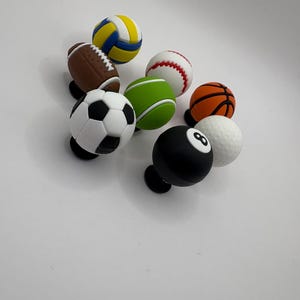 May include: A set of eight miniature sports balls, including a basketball, baseball, football, soccer ball, volleyball, golf ball, and a black and white 8-ball.