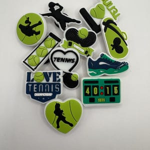 May include: A collection of green and white tennis shoe charms featuring a variety of tennis-themed designs, including players, rackets, balls, and the words "Love Tennis Championship".