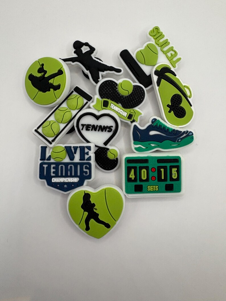 May include: A collection of green and white tennis shoe charms featuring a variety of tennis-themed designs, including players, rackets, balls, and the words "Love Tennis Championship".