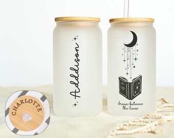 May include: Two frosted glass tumblers with bamboo lids. One features the name "Addison" in black script, the other has a crescent moon, stars, and an open book design. A clear straw is in one. The lid of one tumbler says "Charlotte".