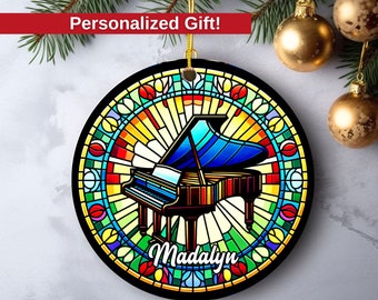 May include: A round, colorful stained glass ornament featuring a grand piano with the name "Madalyn" written below it.