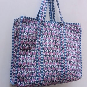 May include: A large tote bag with blue and white striped handles and a floral print in shades of pink and blue.