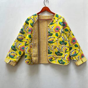 May include: A yellow quilted jacket with a floral print. The jacket has a striped lining and a button closure.