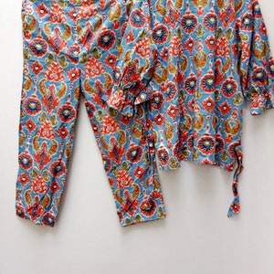 May include: A blue and red patterned pajama set with a long-sleeved top and pants. The top has a round neckline and the pants have a straight leg.