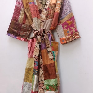 Puede incluir: Una larga bata de patchwork con un estampado floral colorido. La bata está hecha de diferentes telas y tiene un cinturón de atar.