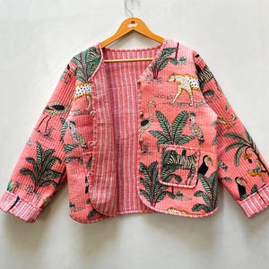 Puede incluir: Una chaqueta acolchada rosa con forro a rayas y un estampado colorido de animales y palmeras.