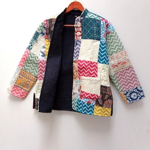May include: A patchwork jacket with a mandarin collar and long sleeves. The jacket features a variety of colorful fabric squares in shades of pink, green, blue, and yellow. The interior lining is solid black.