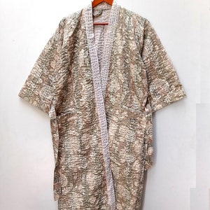 May include: A beige quilted robe with a floral pattern and a white sash. The robe has short sleeves and a shawl collar.