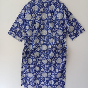 Op de afbeelding: Een blauwe en witte bloemenprint badjas met een zelfbindende riem. De badjas heeft korte mouwen en een kraag.