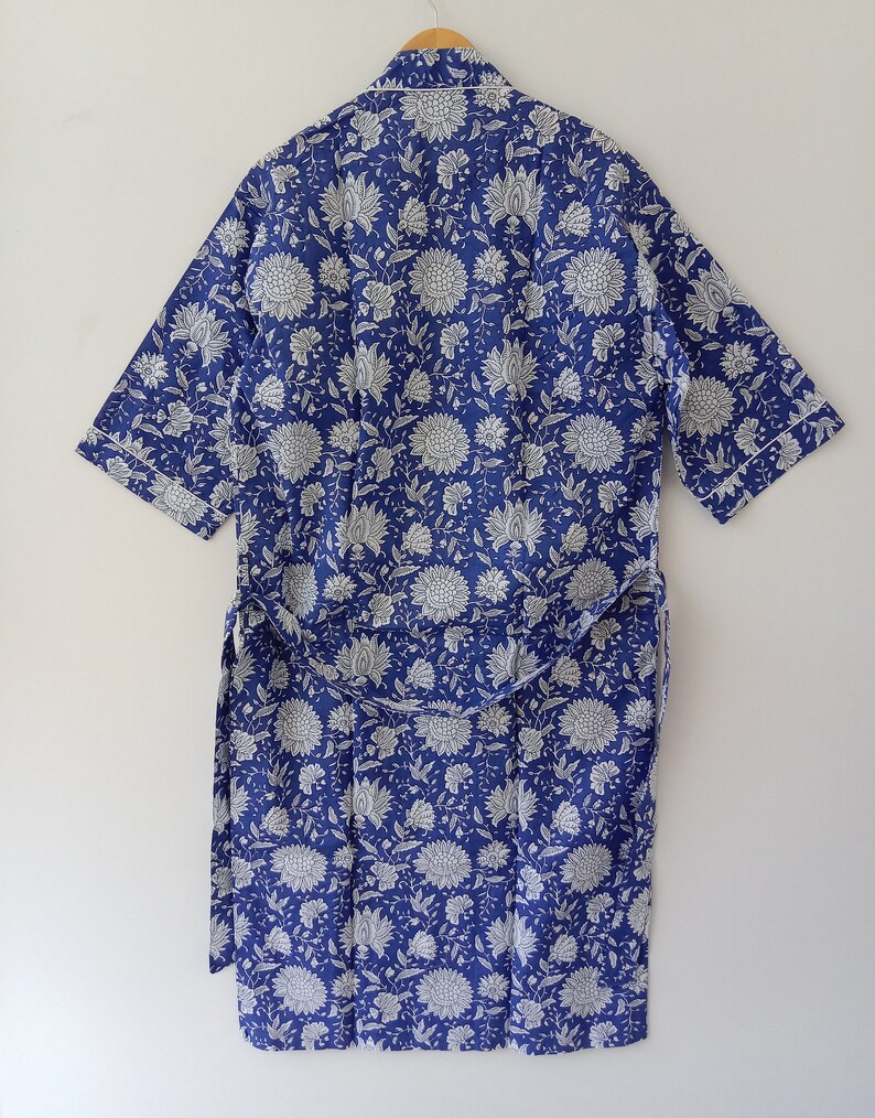 Op de afbeelding: Een blauwe en witte bloemenprint badjas met een zelfbindende riem. De badjas heeft korte mouwen en een kraag.
