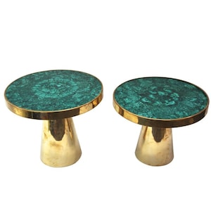 May include: Two side tables with round tops featuring a green malachite pattern. The edges are trimmed with gold, and the pedestal bases are a polished gold color. The tables are designed with a modern aesthetic.