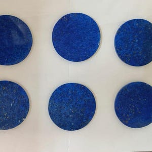 Op de afbeelding: Zes ronde, gepolijste lapis lazuli stenen. De stenen zijn diepblauw van kleur, met gouden en pyriet insluitsels. Elke steen heeft een diameter van ongeveer 5 cm. Geschikt voor het maken van sieraden of decoratieve doeleinden.