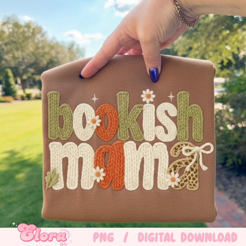 May include: A brown sweatshirt with the words "bookish mama" in a knitted style. The letters are in white, green, and orange with daisy accents. The bottom right of the sweatshirt has a leopard print bow.