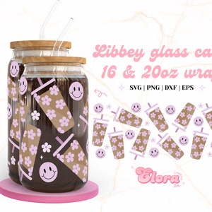 May include: Two glass jars with lids and straws, decorated with a pattern of pink flowers, smiley faces, and brown and pink cups. The jars are labeled "Libbey glass can 16 & 20oz wrap" and "Glora".