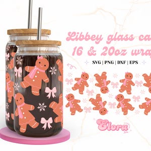 Puede incluir: Dos tarros de vidrio con tapas y pajitas, decorados con un patrón de hombre de jengibre. Los tarros son de 16 y 20 onzas. El diseño incluye lazos rosas y copos de nieve. El texto "Libbey glass can 16 & 20oz wrap SVG | PNG | DXF | EPS Elora" está en la parte superior de la imagen.