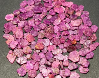 Peut inclure: Un grand tas de pierres précieuses de rubis roses. Les pierres brutes non taillées sont de tailles et de formes variées.