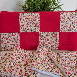 Peut inclure: Une pochette rectangulaire à fermeture éclair avec un motif patchwork floral rouge et crème et une fermeture éclair rouge. La pochette comporte une petite étiquette brodée dans le coin inférieur droit. Trois carrés de tissu à motif floral sont placés devant.