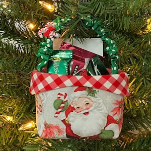 May include: A red and white gingham fabric Christmas stocking with a Santa Claus design. The stocking is filled with candy canes and small wrapped gifts.