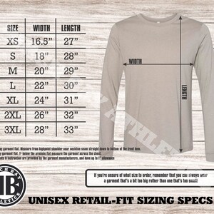 Puede incluir: Una tabla de tallas para camisas de manga larga unisex con medidas en pulgadas. La tabla muestra el ancho y la longitud de las camisas en tallas XS a 3XL. La tabla est&aacute; sobre un fondo de madera.