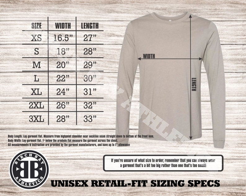 Puede incluir: Una tabla de tallas para camisas de manga larga unisex con medidas en pulgadas. La tabla muestra el ancho y la longitud de las camisas en tallas XS a 3XL. La tabla est&aacute; sobre un fondo de madera.