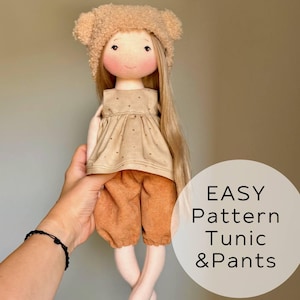 May include: A handmade doll with long blonde hair, wearing a tan tunic, orange shorts, and a bear-eared hat. The doll has a painted face with rosy cheeks. The text "EASY Pattern Tunic & Pants" is on the right side of the image.