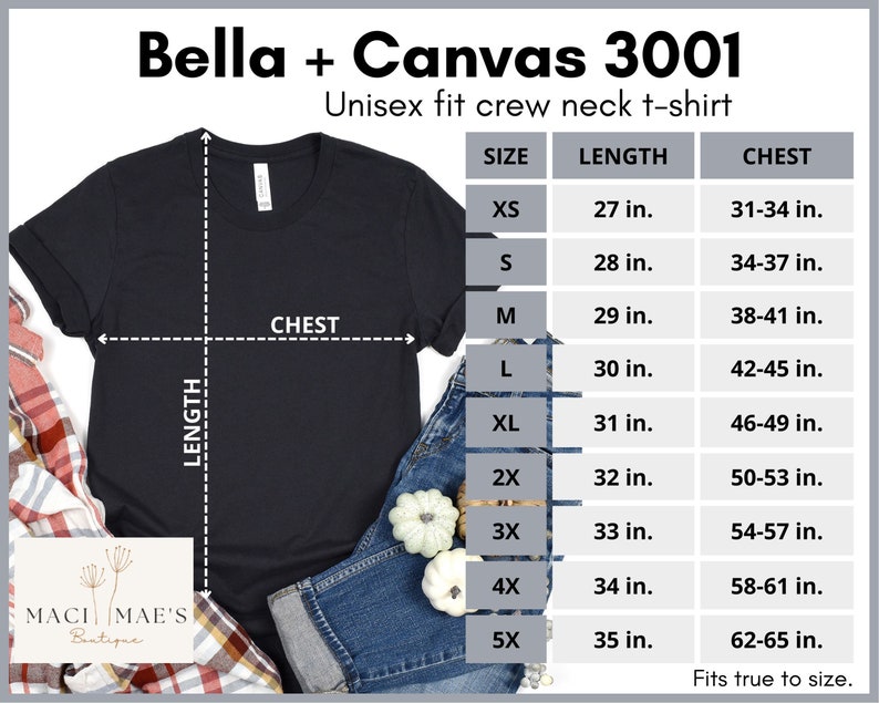 May include: A black unisex crew neck t-shirt with size chart showing measurements in inches. The chart includes sizes XS, S, M, L, XL, 2X, 3X, 4X, and 5X. The t-shirt is laid flat on a plaid surface with a pair of jeans and pumpkins.