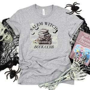 May include: Gray t-shirt with a graphic of a stack of books, bats, and a skull with the text "Salem Witch Book Club".