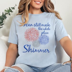 May include: A light blue t-shirt with a graphic of fireworks and the text "I can still make the whole place shimmer".