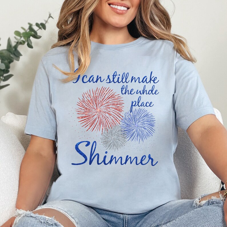 May include: A light blue t-shirt with a graphic of fireworks and the text "I can still make the whole place shimmer".