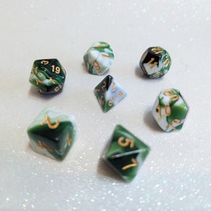 May include: Set of seven green and white dice with gold numbers. The dice are made of a marbled plastic material.