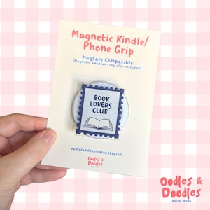May include: A white card with a magnetic phone grip featuring a blue and white design that reads "BOOK LOVERS CLUB" with an open book illustration. The card also has the text "Magnetic Kindle/ Phone Grip" and "MagSafe Compatible".
