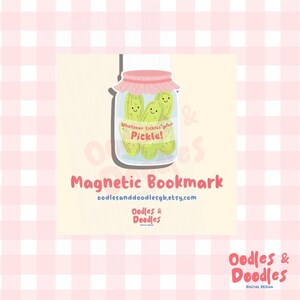 A hand holding a magnetic bookmark of a pink and green jar of pickles with a label saying "Whatever tickles your pickle!" on a square backing card.