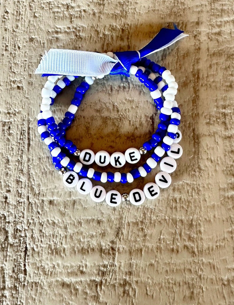 Set of 3 Duke beaded bracelets. The first is blue and white color blocked Duke lettering. The second is blue with white accents with Blue Devils lettering. The third is blue and white beads