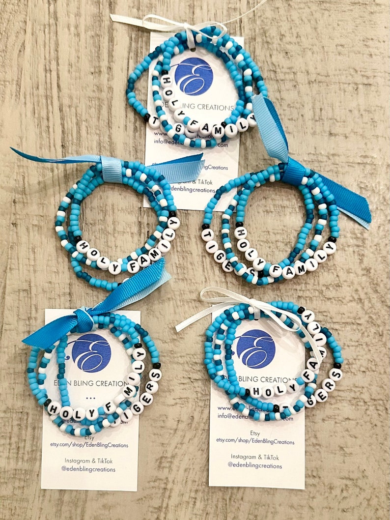 Five sets of Holy Family Tigers College Bracelets. Light blue and teal beaded stretch bracelets